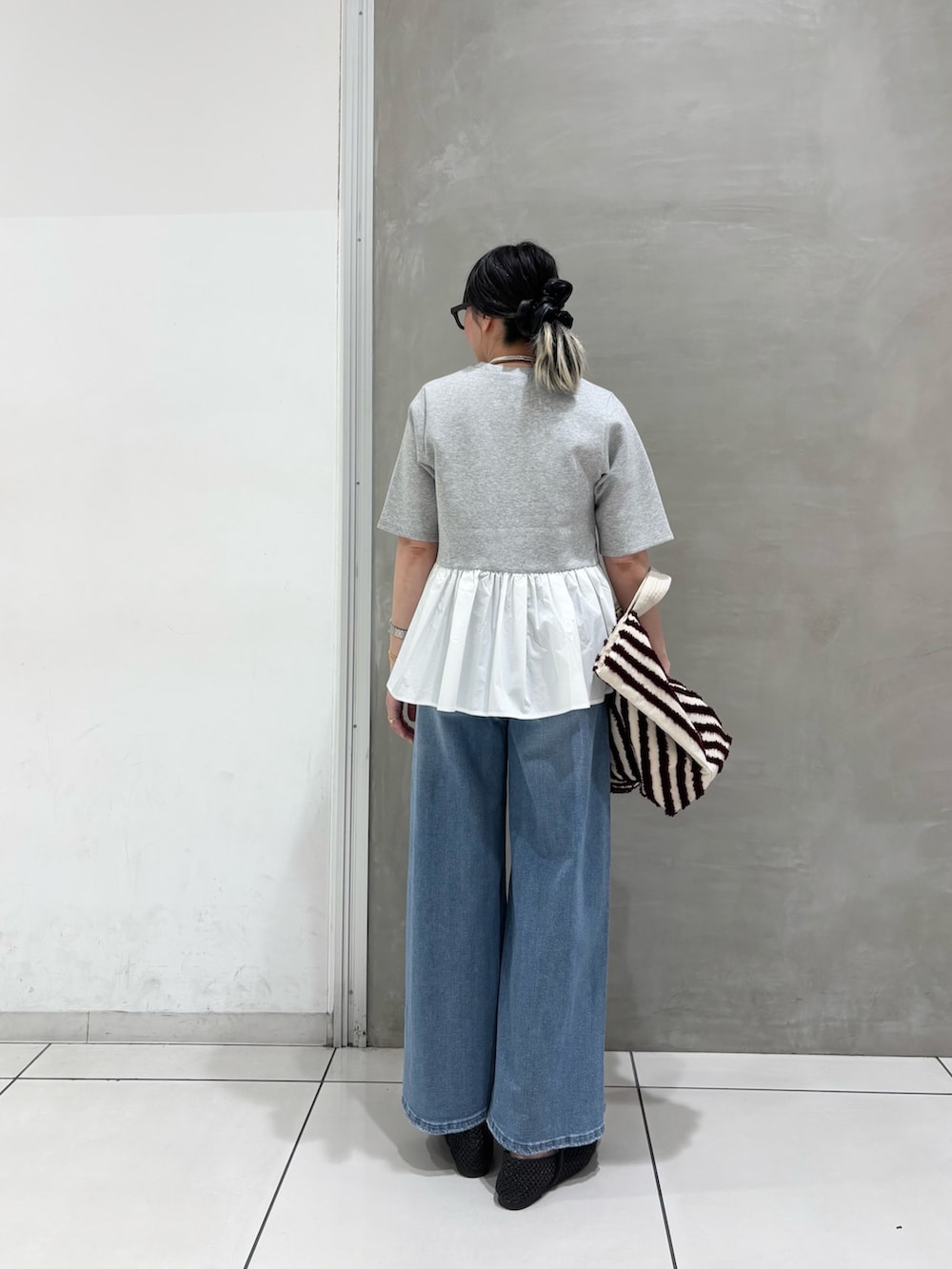 グレー系のTシャツ/カットソー、ブラウン系のバッグ、ブルー系のデニムパンツを着用したレディースの春コーディネートの2枚目の写真