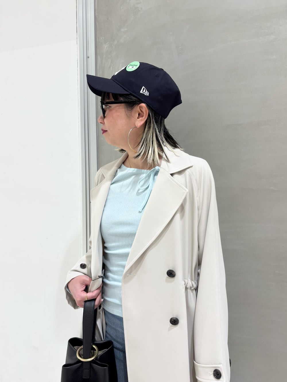 ブルー系のデニムパンツ、ブラック系のハンドバッグ、ブラウン系のスニーカーを着用したレディースの春コーディネートの6枚目の写真