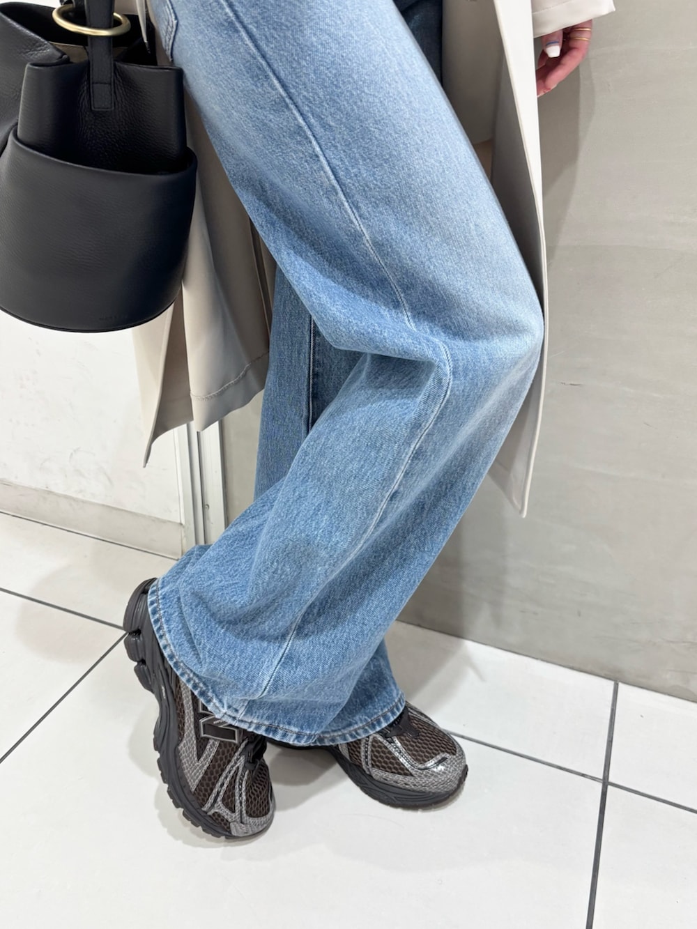 ブルー系のデニムパンツ、ブラック系のハンドバッグ、ブラウン系のスニーカーを着用したレディースの春コーディネートの8枚目の写真