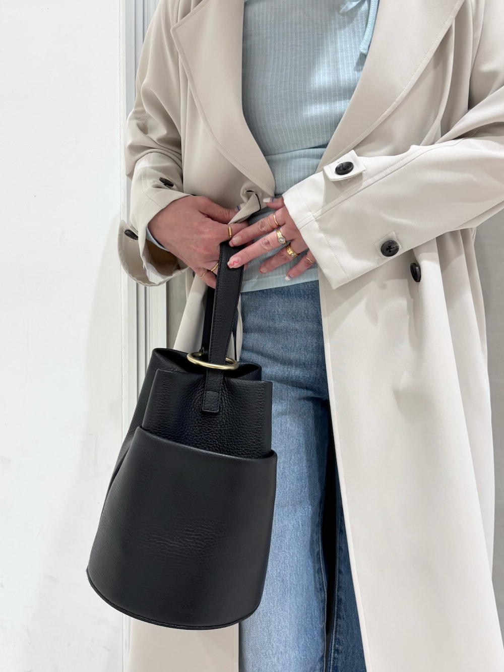 ブルー系のデニムパンツ、ブラック系のハンドバッグ、ブラウン系のスニーカーを着用したレディースの春コーディネートの7枚目の写真