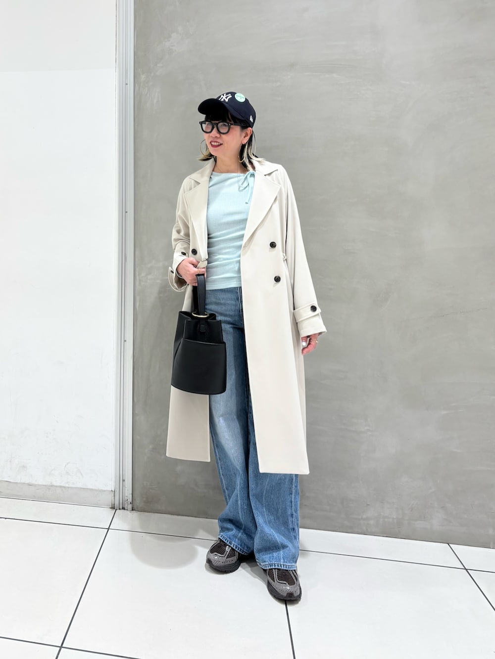 ブルー系のデニムパンツ、ブラック系のハンドバッグ、ブラウン系のスニーカーを着用したレディースの春コーディネートの2枚目の写真