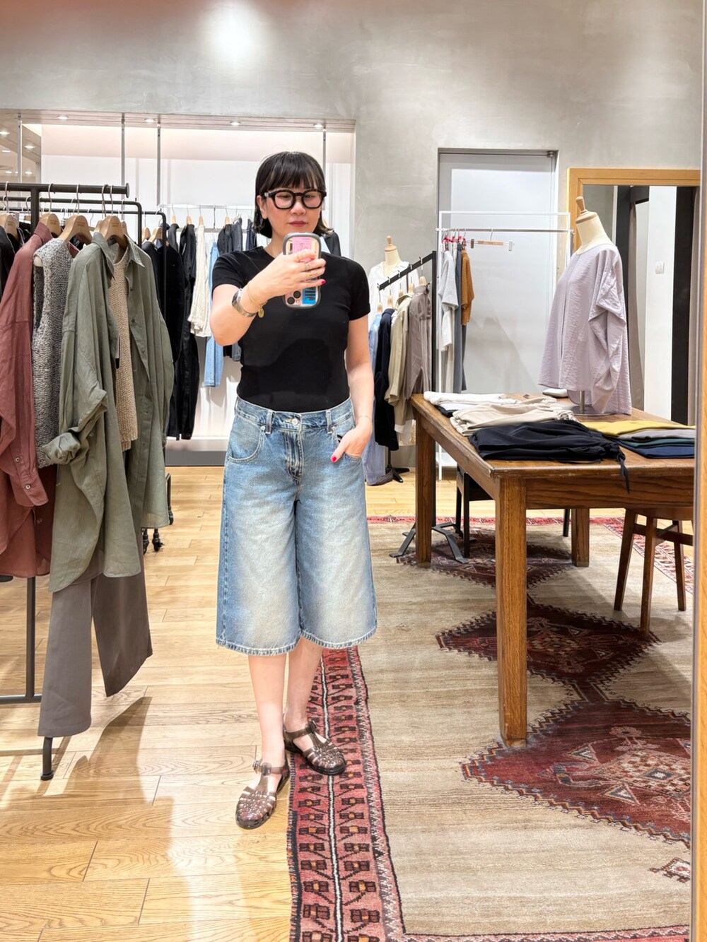 ブラック系のTシャツ/カットソー、オレンジ系のトートバッグ、ブルー系のデニムパンツを着用したレディースの春コーディネートの3枚目の写真
