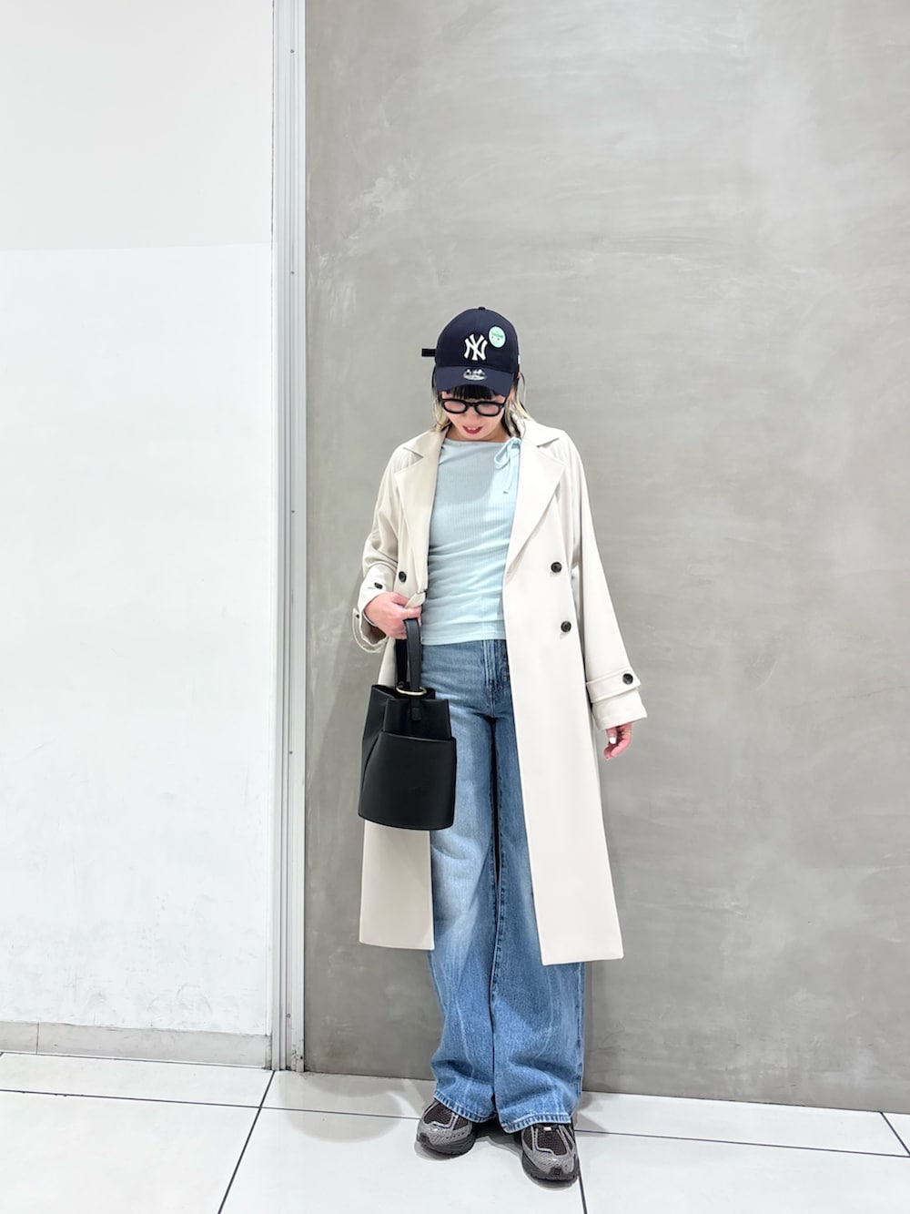 ブルー系のデニムパンツ、ブラック系のハンドバッグ、ブラウン系のスニーカーを着用したレディースの春コーディネートの5枚目の写真