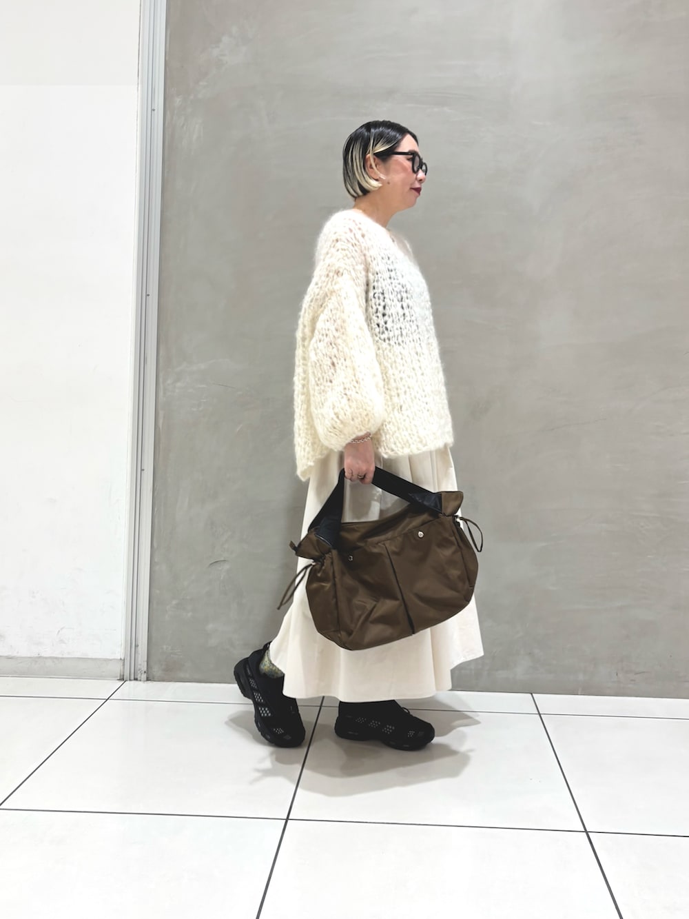 ホワイト系のニット/セーター、ホワイト系のスカート、ブラウン系のショルダーバッグを着用したレディースの秋コーディネートの2枚目の写真