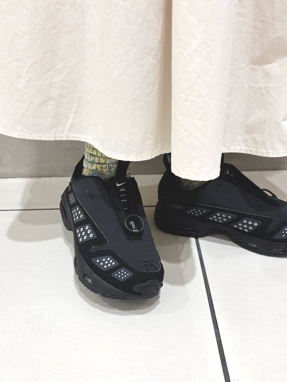 ホワイト系のニット/セーター、ホワイト系のスカート、ブラウン系のショルダーバッグを着用したレディースの秋コーディネートの6枚目の写真