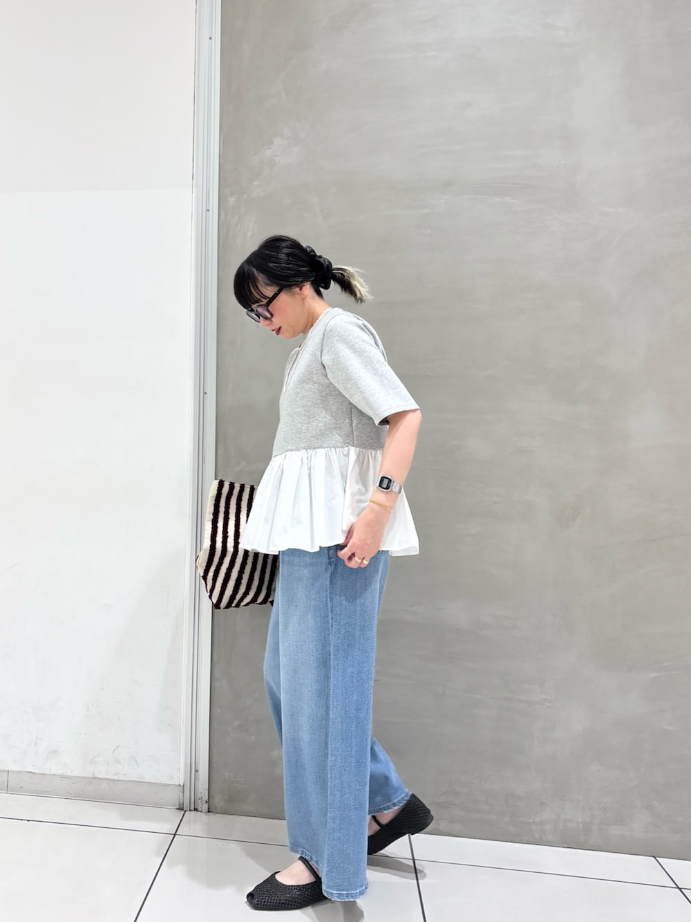 グレー系のTシャツ/カットソー、ブラウン系のバッグ、ブルー系のデニムパンツを着用したレディースの春コーディネートの3枚目の写真