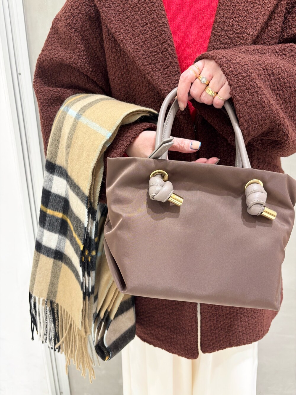 ブラウン系のその他アウター、レッド系のニット/セーター、ホワイト系のその他パンツを着用したレディースの冬コーディネートの5枚目の写真