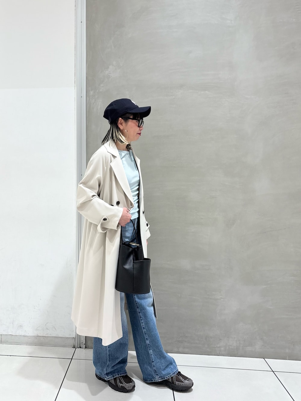 ブルー系のデニムパンツ、ブラック系のハンドバッグ、ブラウン系のスニーカーを着用したレディースの春コーディネートの3枚目の写真