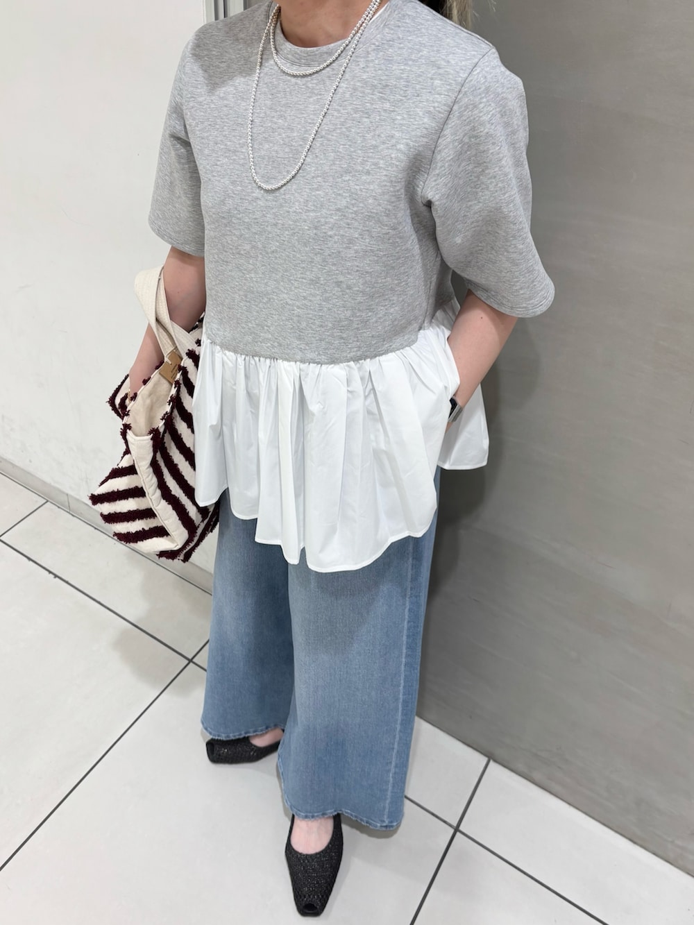 グレー系のTシャツ/カットソー、ブラウン系のバッグ、ブルー系のデニムパンツを着用したレディースの春コーディネートの5枚目の写真