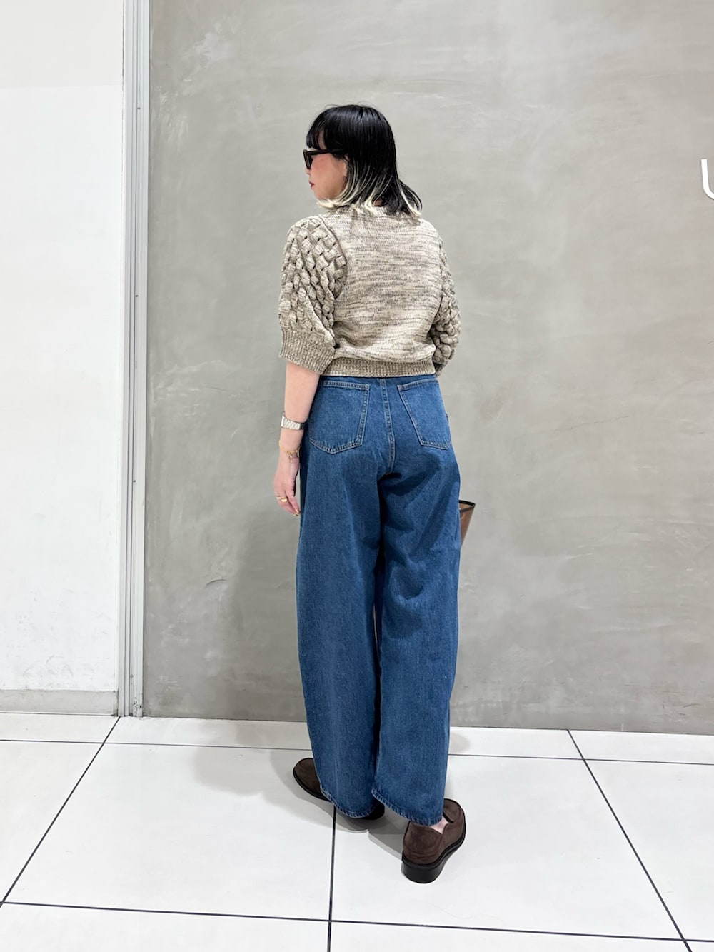 ホワイト系のニット/セーター、ブルー系のデニムパンツ、ブラウン系のローファーを着用したレディースの春コーディネートの3枚目の写真