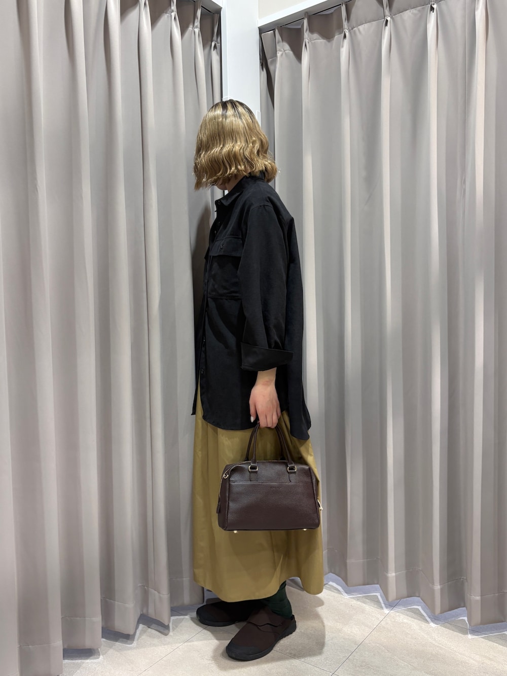 ブラック系のシャツ/ブラウス、イエロー系のスカートを着用したレディースの春コーディネートの2枚目の写真