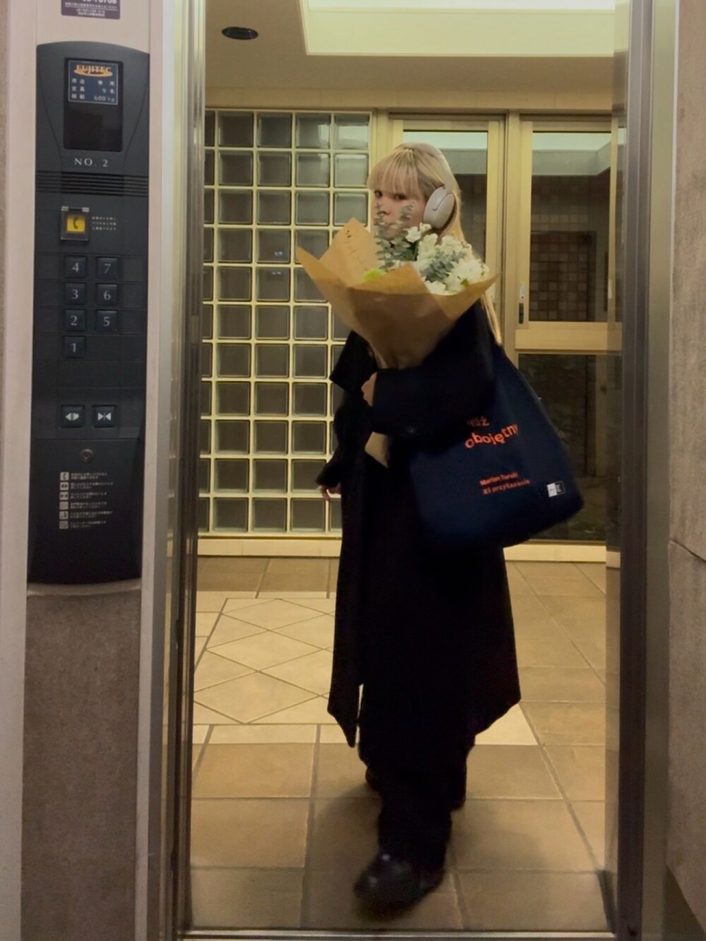 ブラック系のチェスターコート、ブラック系のスニーカー、ホワイト系のその他を着用したレディースの冬コーディネートの2枚目の写真