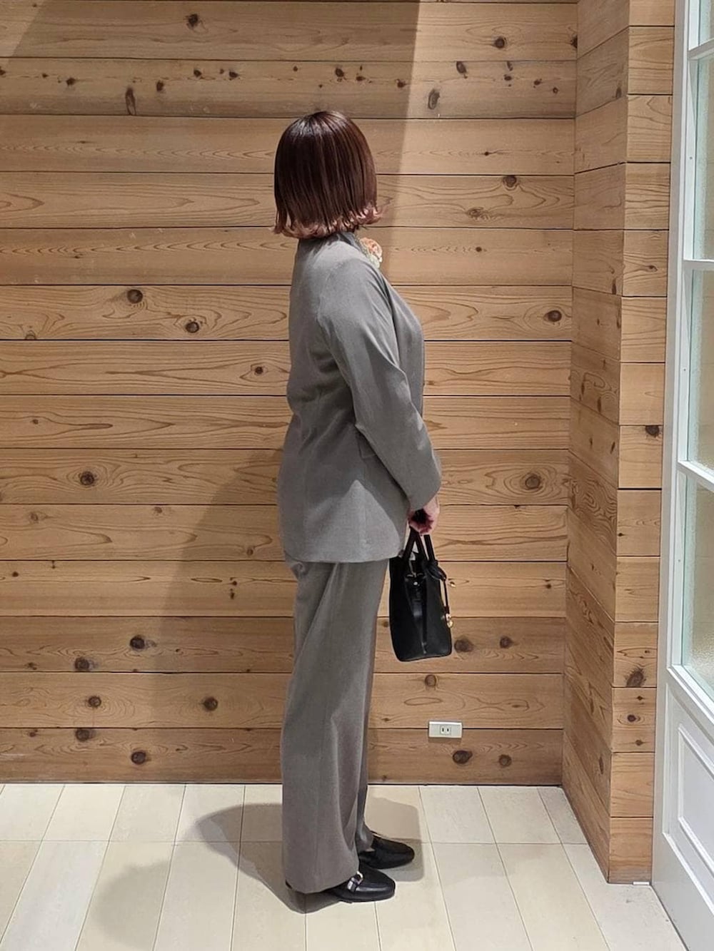 ブラック系のローファー、ブラック系のショルダーバッグ、ブラウン系のスラックスを着用したレディースの春コーディネートの2枚目の写真