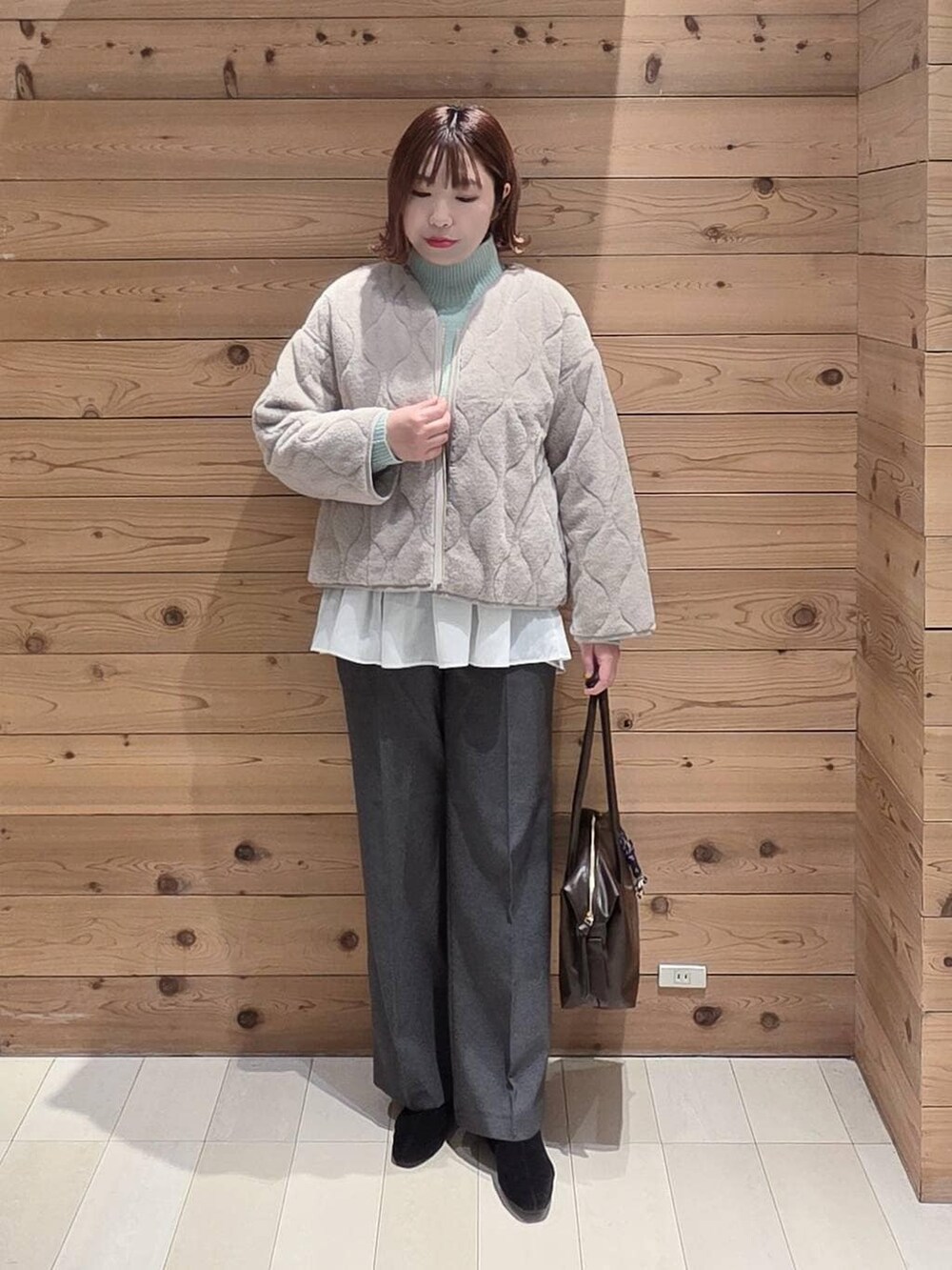 ベージュ系のブルゾン、ブラウン系のボストンバッグ、グリーン系のニット/セーターを着用したレディースの冬コーディネートの4枚目の写真