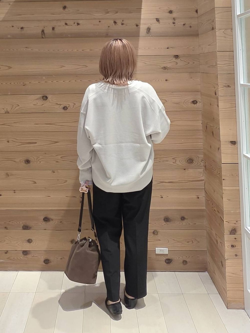 ブラウン系のショルダーバッグ、ブラック系のバレエシューズ、ホワイト系のTシャツ/カットソーを着用したレディースの秋コーディネートの3枚目の写真