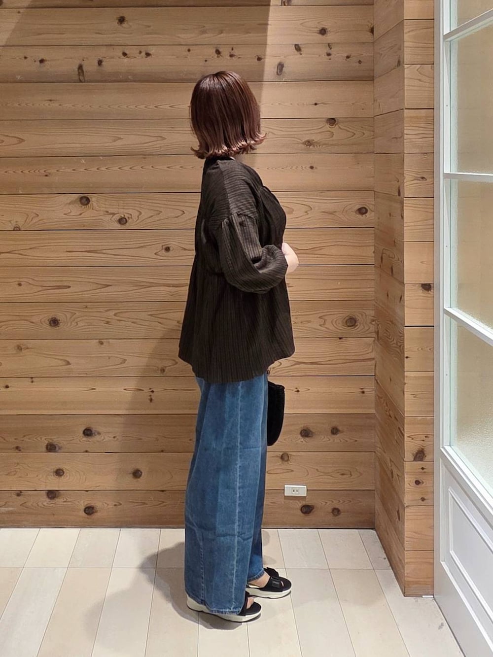 ブルー系のデニムパンツ、ブラック系のタンクトップ、ブラック系のクラッチバッグを着用したレディースの春コーディネートの2枚目の写真