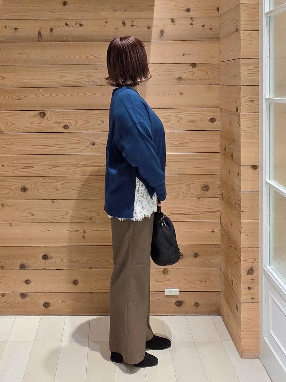 ベージュ系のダウンジャケット/コート、ブラック系のハンドバッグ、ブルー系のニット/セーターを着用したレディースの冬コーディネートの2枚目の写真