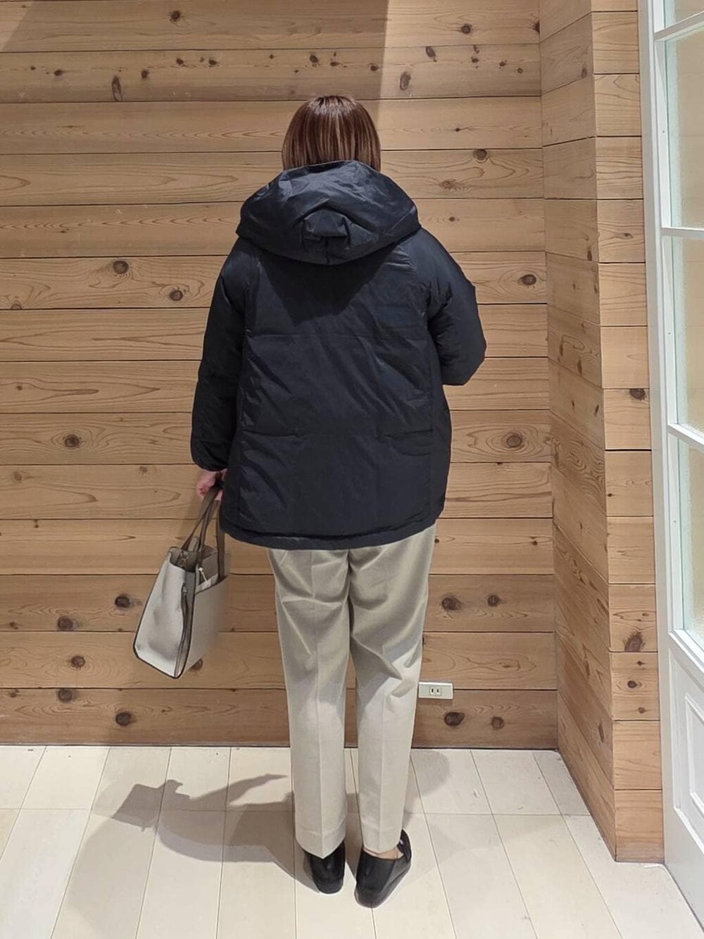 ブラック系のローファー、ホワイト系のショルダーバッグ、ブラック系のダウンジャケット/コートを着用したレディースの冬コーディネートの3枚目の写真