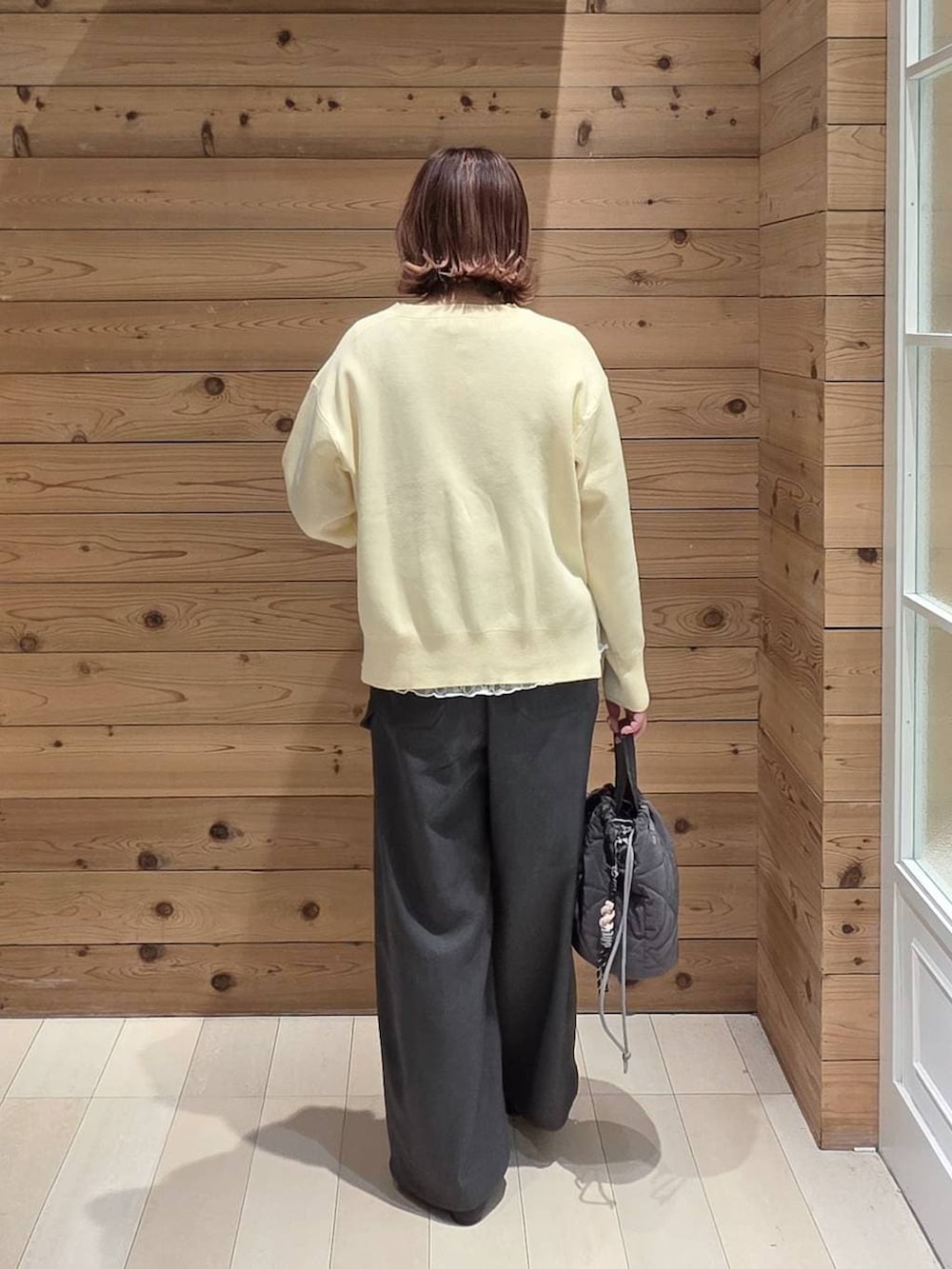 ブラック系のパンプス、グレー系のハンドバッグ、イエロー系のニット/セーターを着用したレディースの春コーディネートの3枚目の写真