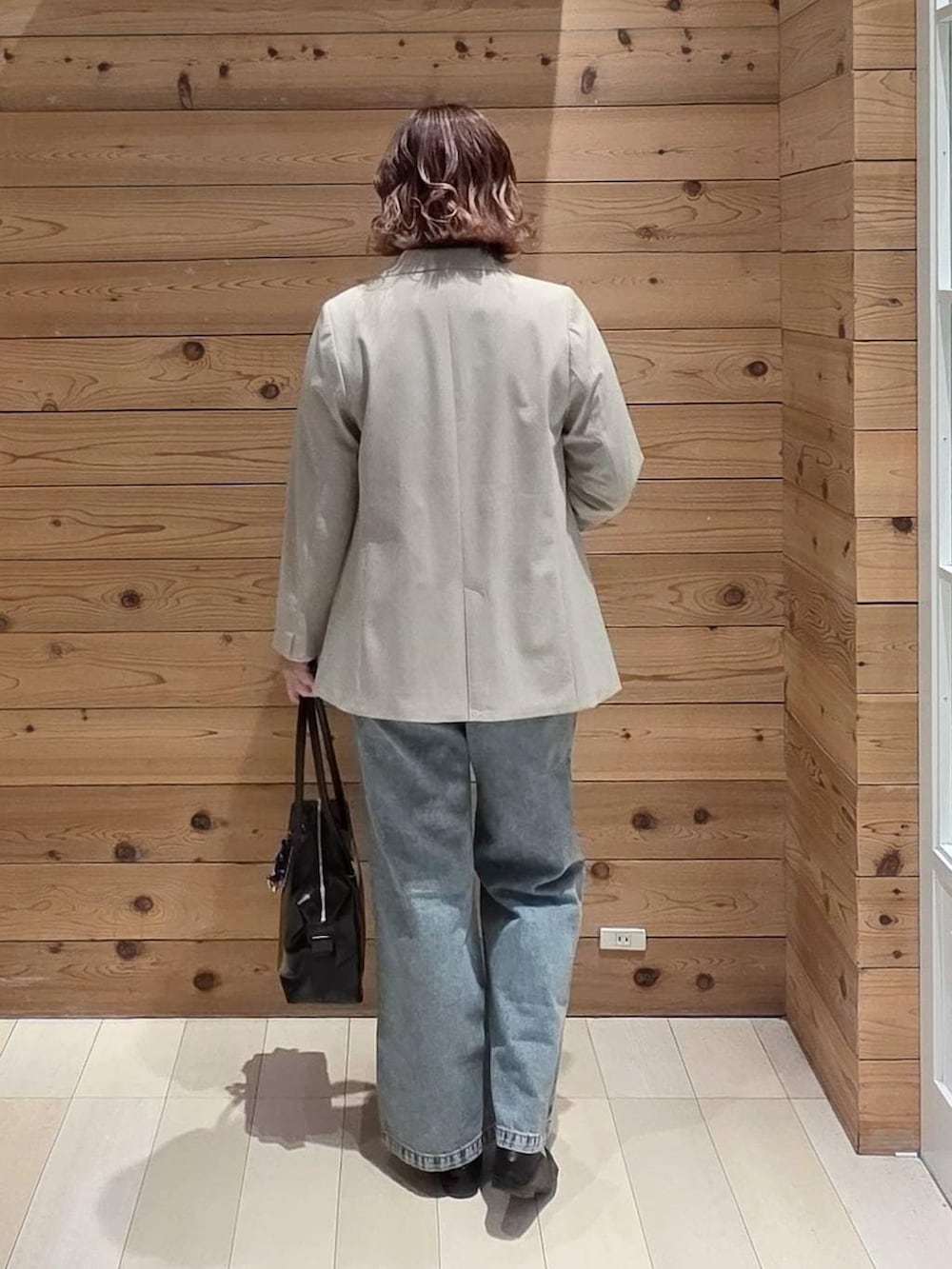 ブラック系のローファー、ブラック系のボストンバッグ、ブルー系のデニムパンツを着用したレディースの春コーディネートの3枚目の写真