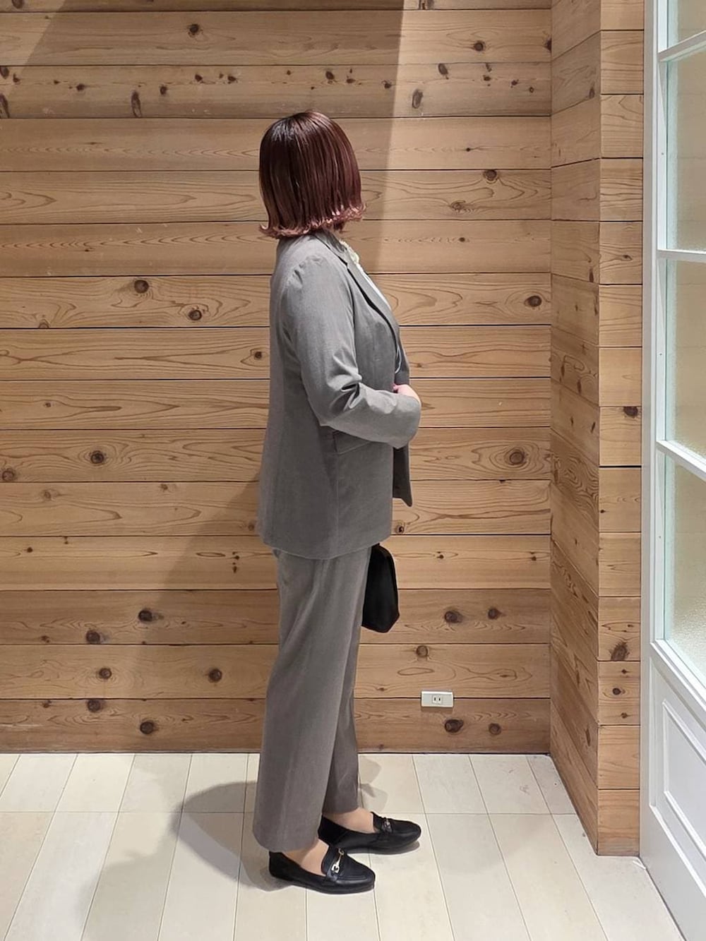 ブラック系のローファー、ブラック系のショルダーバッグ、ブラウン系のスラックスを着用したレディースの冬コーディネートの2枚目の写真