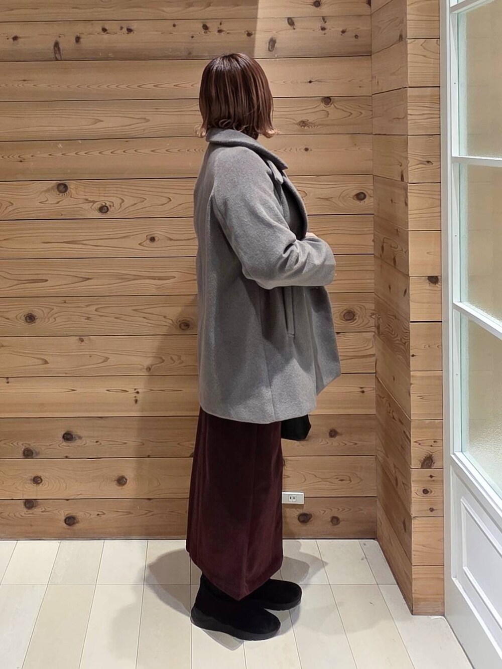 ブラック系のショルダーバッグ、ブラウン系のチェスターコート、レッド系のスカートを着用したレディースの冬コーディネートの2枚目の写真