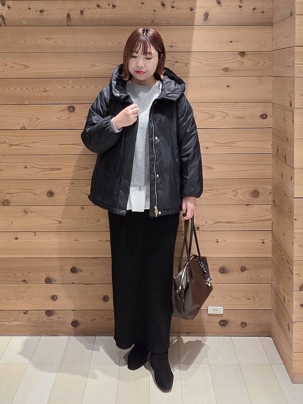 ブルー系のダウンジャケット/コート、ブラウン系のボストンバッグ、ホワイト系のTシャツ/カットソーを着用したレディースの冬コーディネートの4枚目の写真