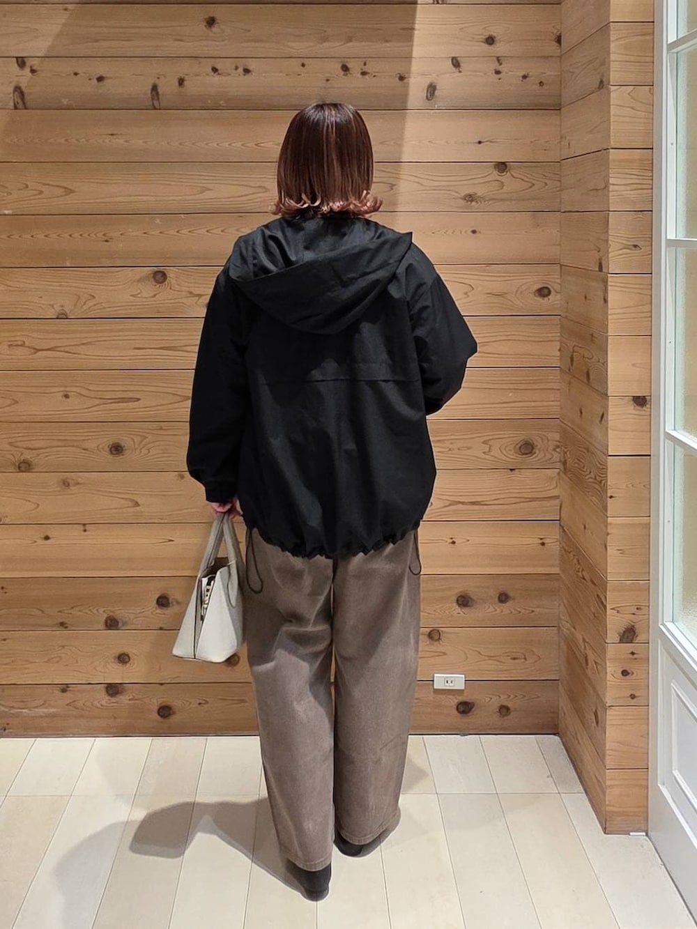 ブラック系のパンプス、ホワイト系のショルダーバッグ、ブラック系のマウンテンパーカーを着用したレディースの春コーディネートの3枚目の写真