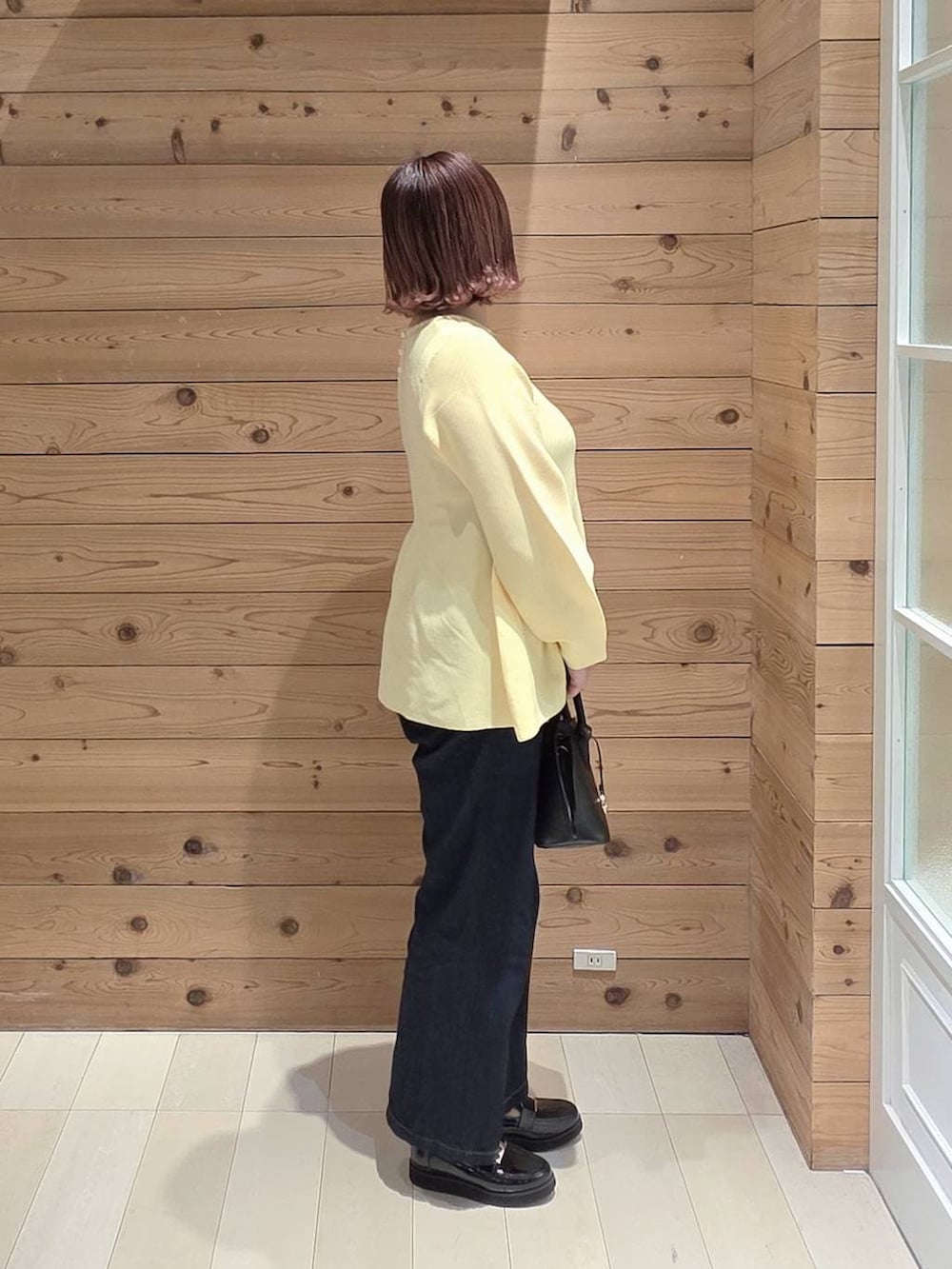 ブラック系のローファー、ブラック系のショルダーバッグ、ブルー系のデニムパンツを着用したレディースの冬コーディネートの2枚目の写真