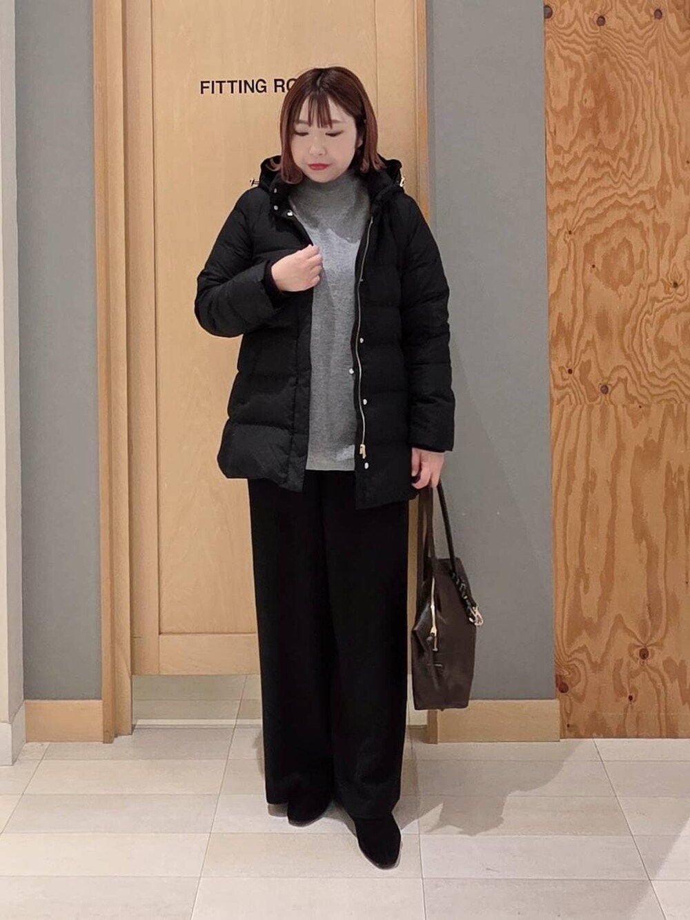 ブラウン系のボストンバッグ、ブラック系のダウンジャケット/コート、グレー系のニット/セーターを着用したレディースの冬コーディネートの4枚目の写真