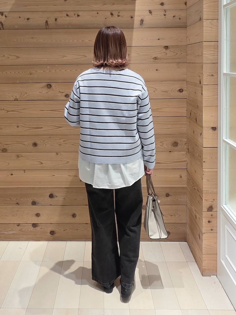 ブラック系のローファー、ホワイト系のショルダーバッグ、ブラック系のデニムパンツを着用したレディースの春コーディネートの3枚目の写真