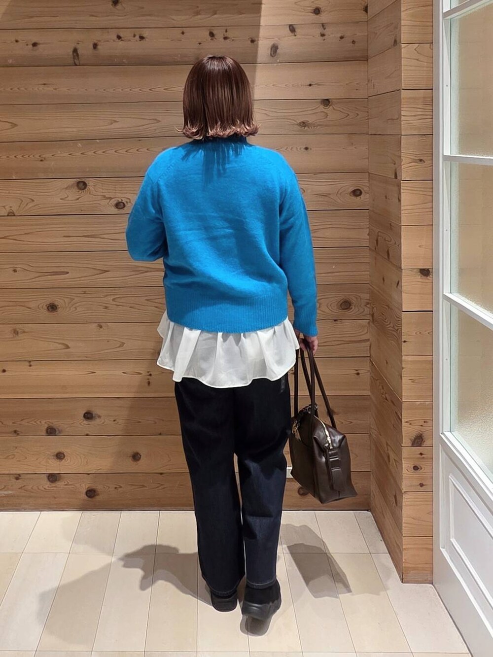 ベージュ系のダウンジャケット/コート、ブラウン系のボストンバッグ、ブルー系のデニムパンツを着用したレディースの冬コーディネートの3枚目の写真