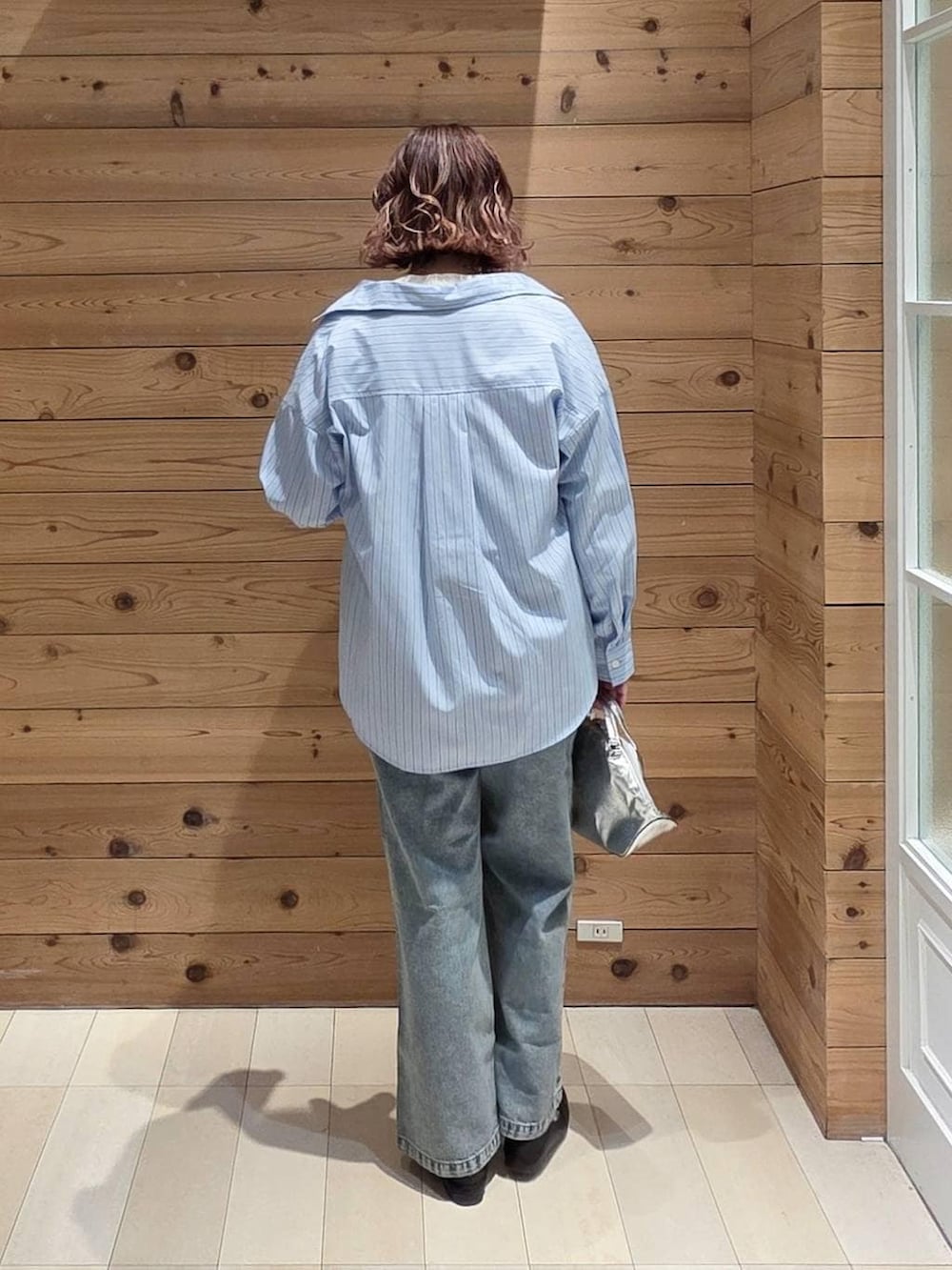 ブラック系のローファー、シルバー系のショルダーバッグ、ブルー系のデニムパンツを着用したレディースの春コーディネートの3枚目の写真