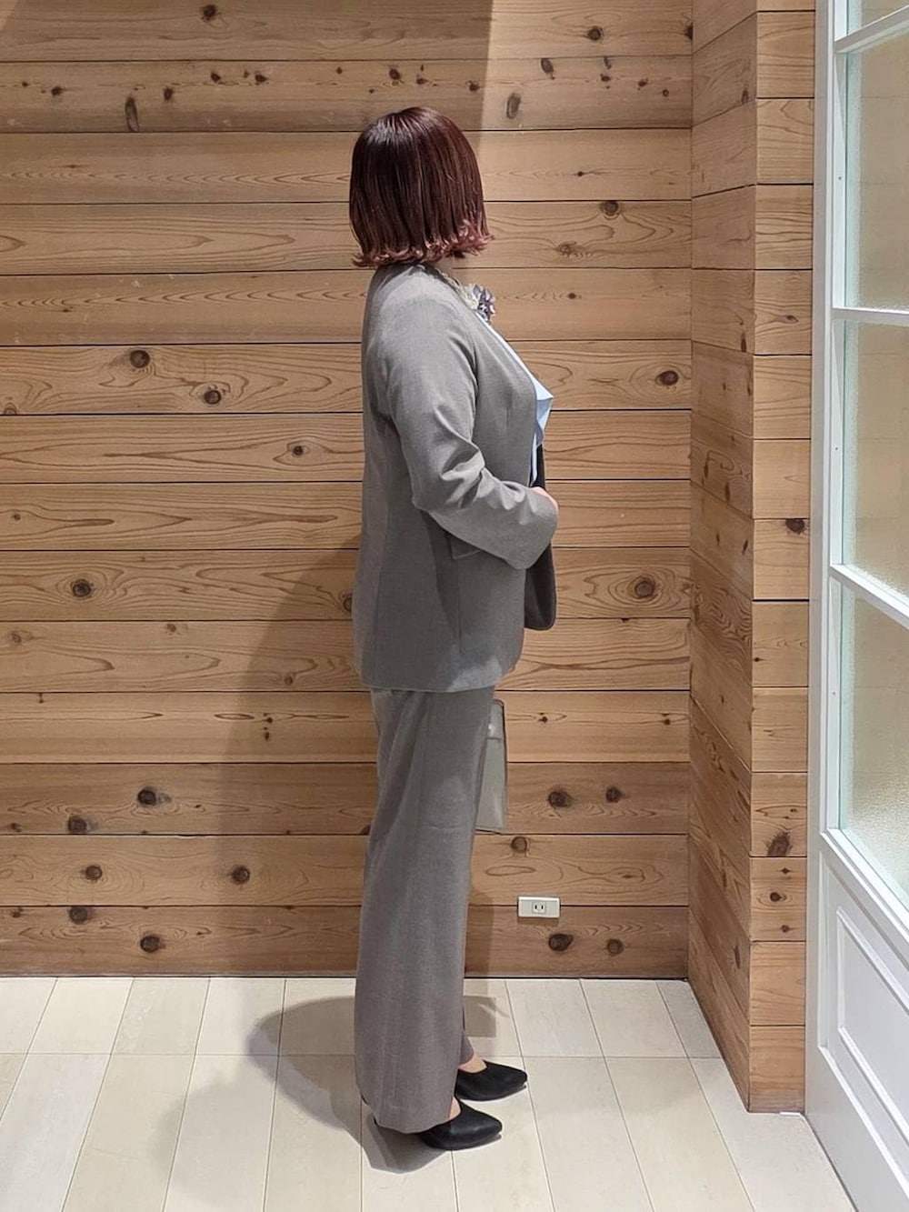 ホワイト系のショルダーバッグ、ブラック系のパンプス、ブラウン系のスラックスを着用したレディースの冬コーディネートの2枚目の写真