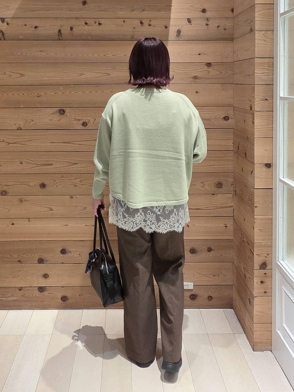 グリーン系のニット/セーター、ブラック系のダウンジャケット/コート、ブラック系のボストンバッグを着用したレディースの冬コーディネートの3枚目の写真