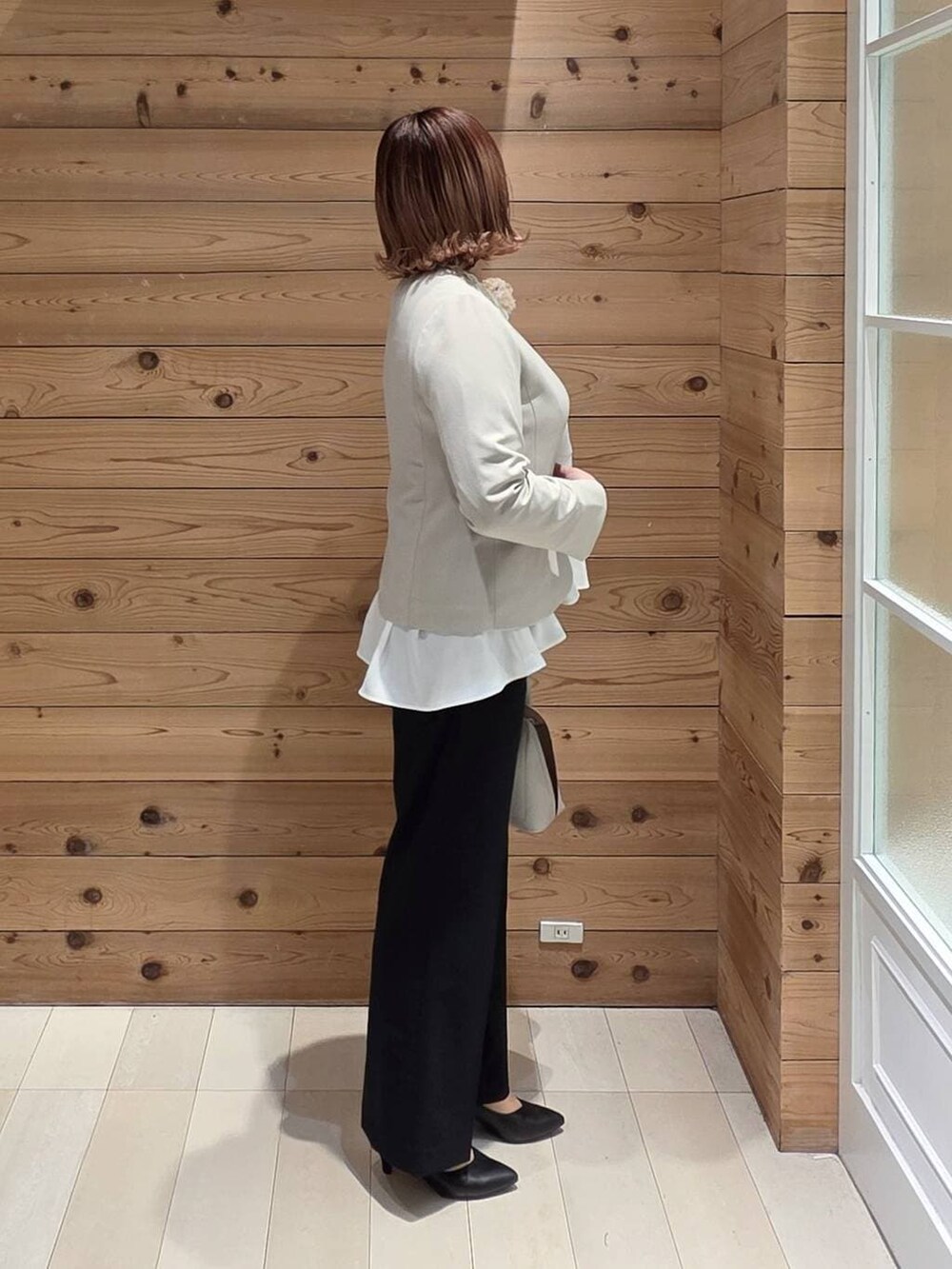 ホワイト系のショルダーバッグ、ブラック系のパンプス、ベージュ系のセットアップを着用したレディースの冬コーディネートの2枚目の写真