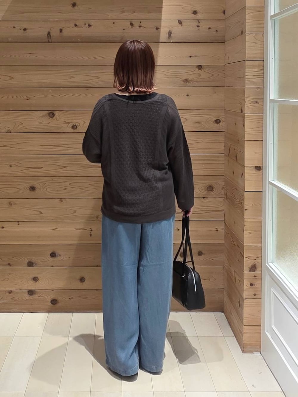 ブラック系のローファー、ブラック系のショルダーバッグ、ブルー系のデニムパンツを着用したレディースの春コーディネートの3枚目の写真