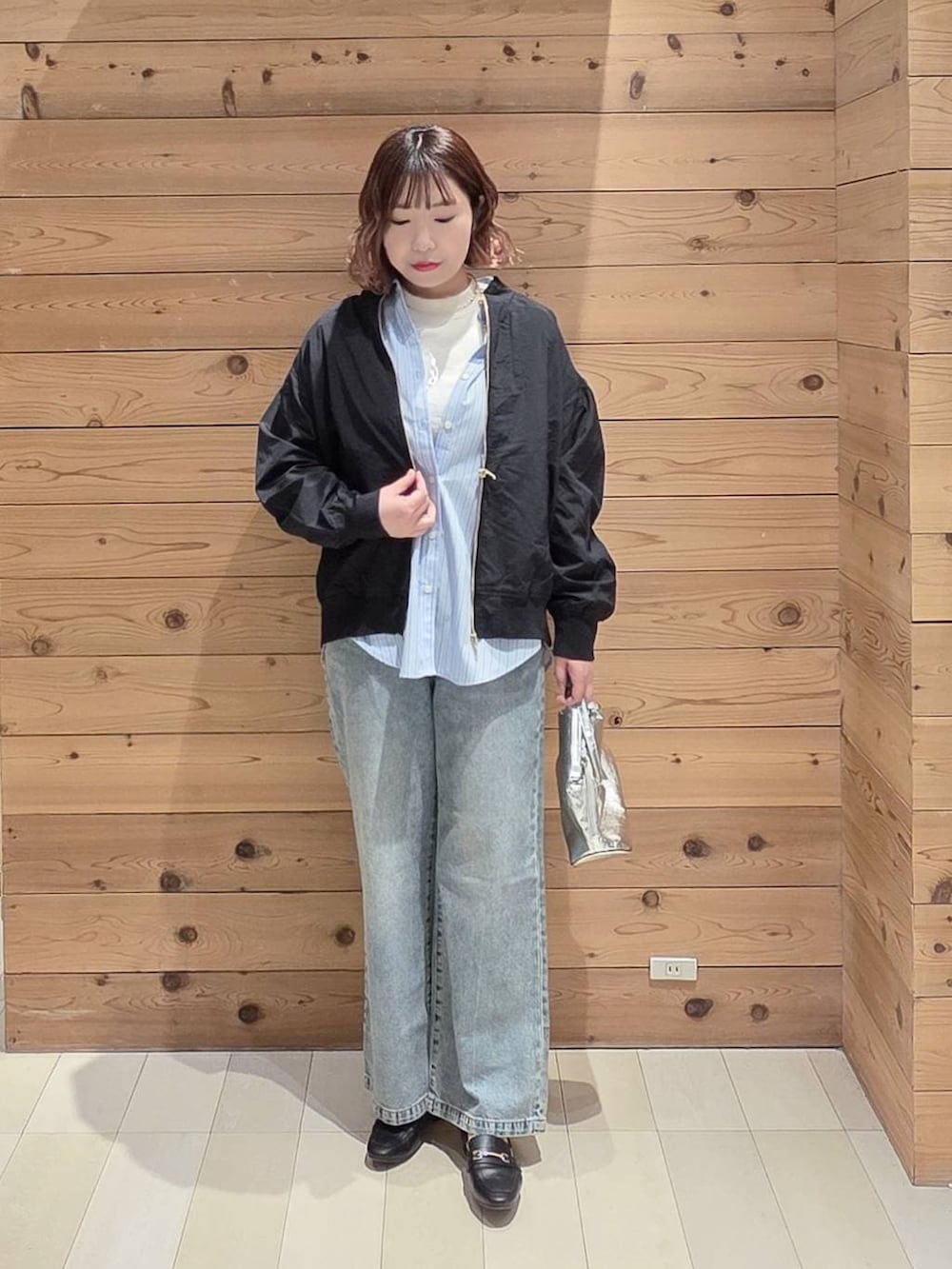 ブラック系のローファー、シルバー系のショルダーバッグ、ブルー系のデニムパンツを着用したレディースの春コーディネートの4枚目の写真