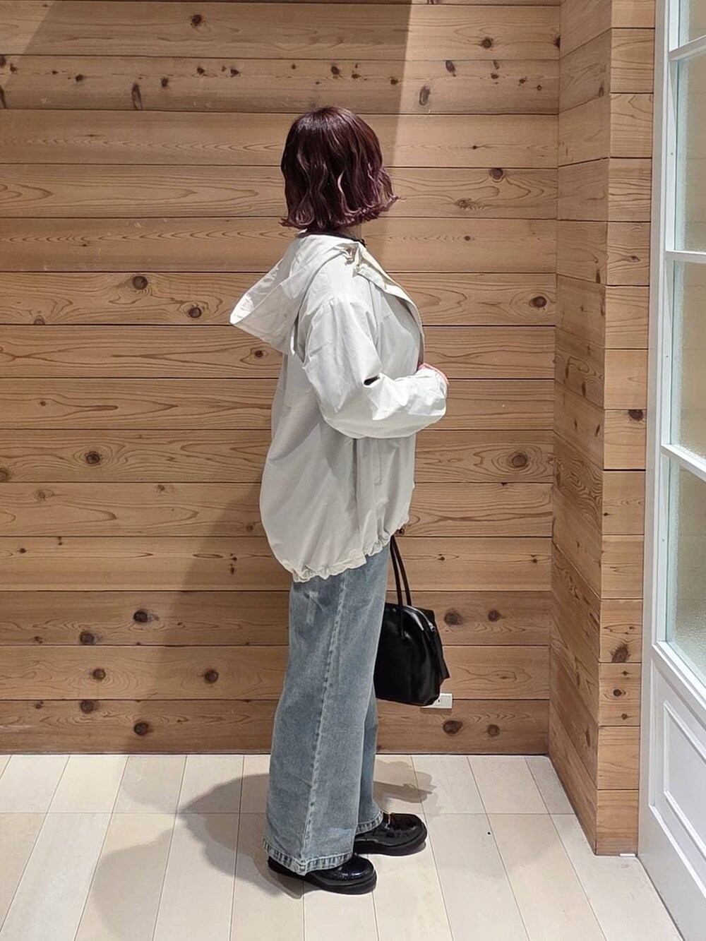 ブラック系のローファー、ブラック系のボストンバッグ、ブルー系のデニムパンツを着用したレディースの冬コーディネートの2枚目の写真