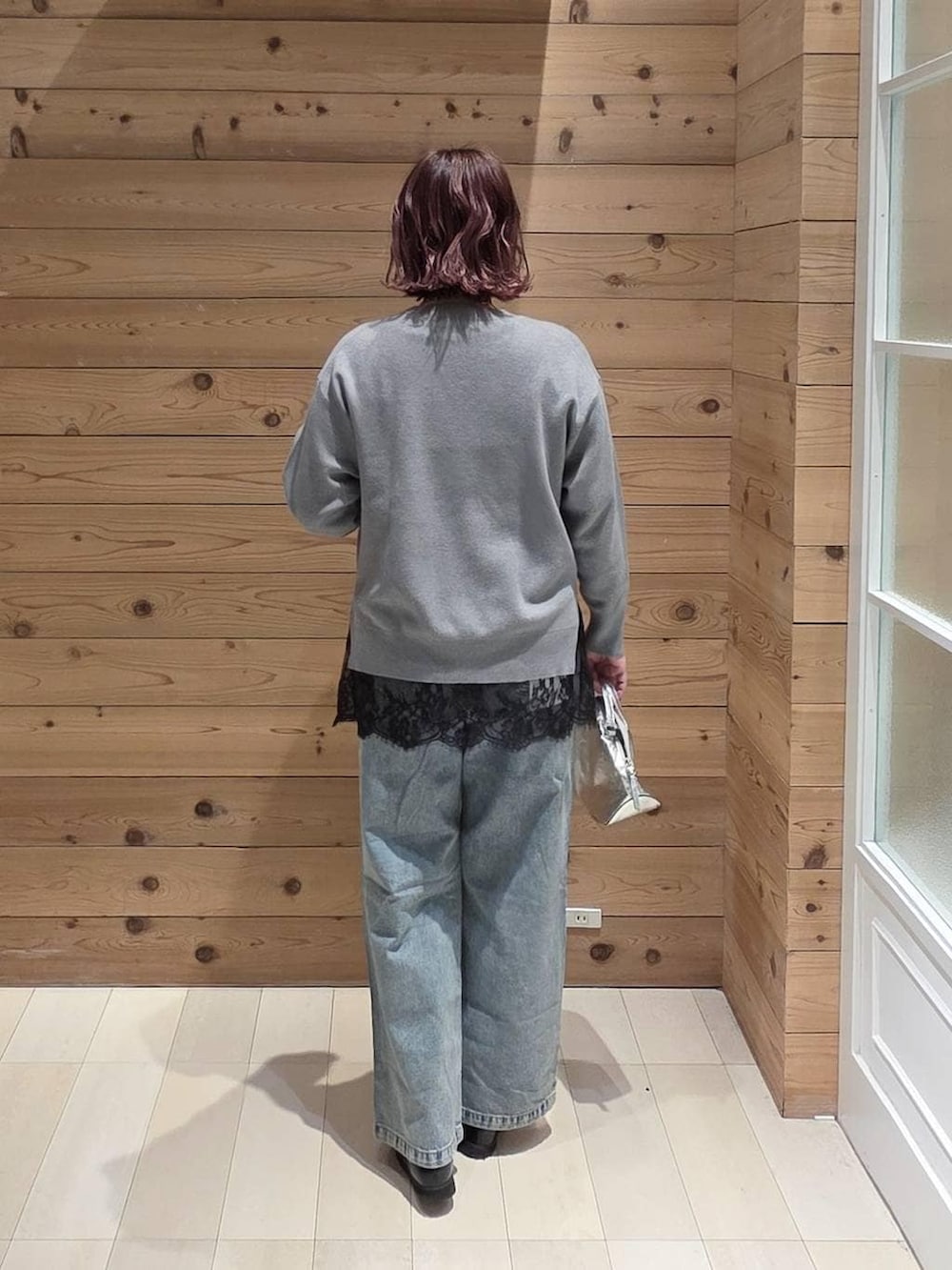 シルバー系のショルダーバッグ、ブラック系のローファー、ブルー系のデニムパンツを着用したレディースの冬コーディネートの3枚目の写真