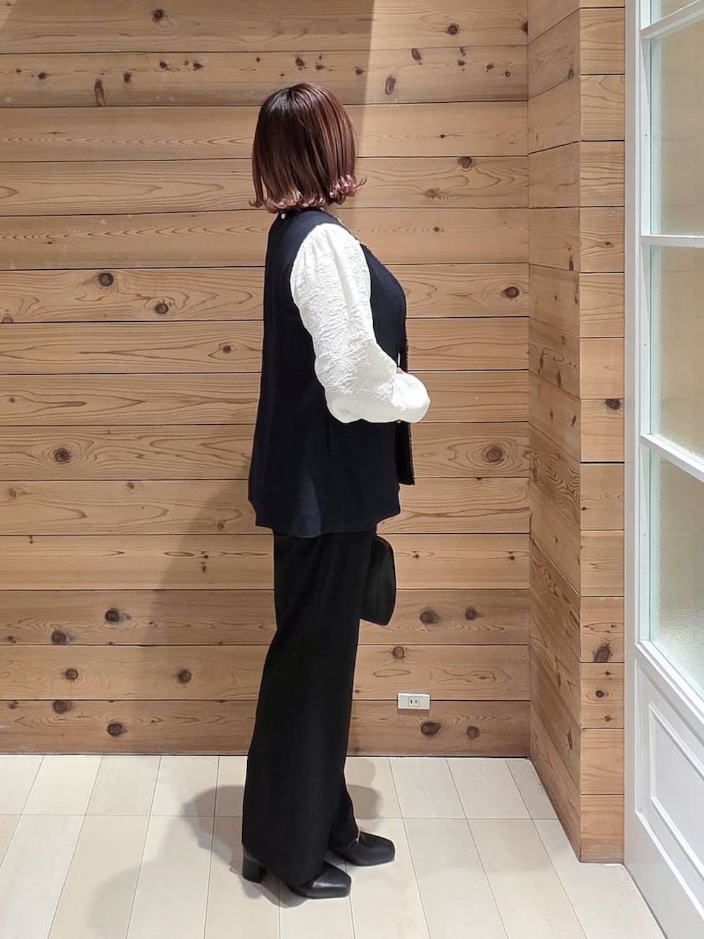 ブラック系のローファー、ブラック系のショルダーバッグ、ブラック系のスラックスを着用したレディースの春コーディネートの2枚目の写真