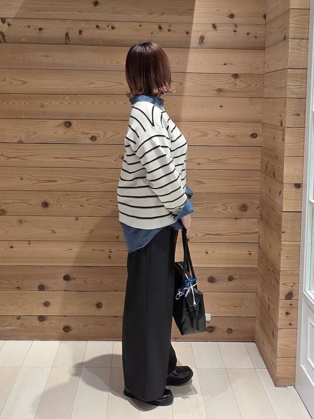 ブラック系のローファー、ブラック系のボストンバッグ、ブルー系のシャツ/ブラウスを着用したレディースの春コーディネートの2枚目の写真