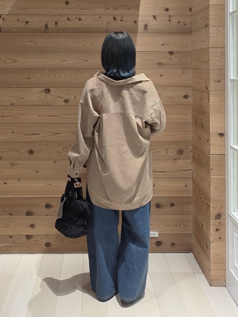 ブルー系のデニムパンツ、ブラック系のバレエシューズ、ブラック系のトートバッグを着用したレディースの秋コーディネートの3枚目の写真