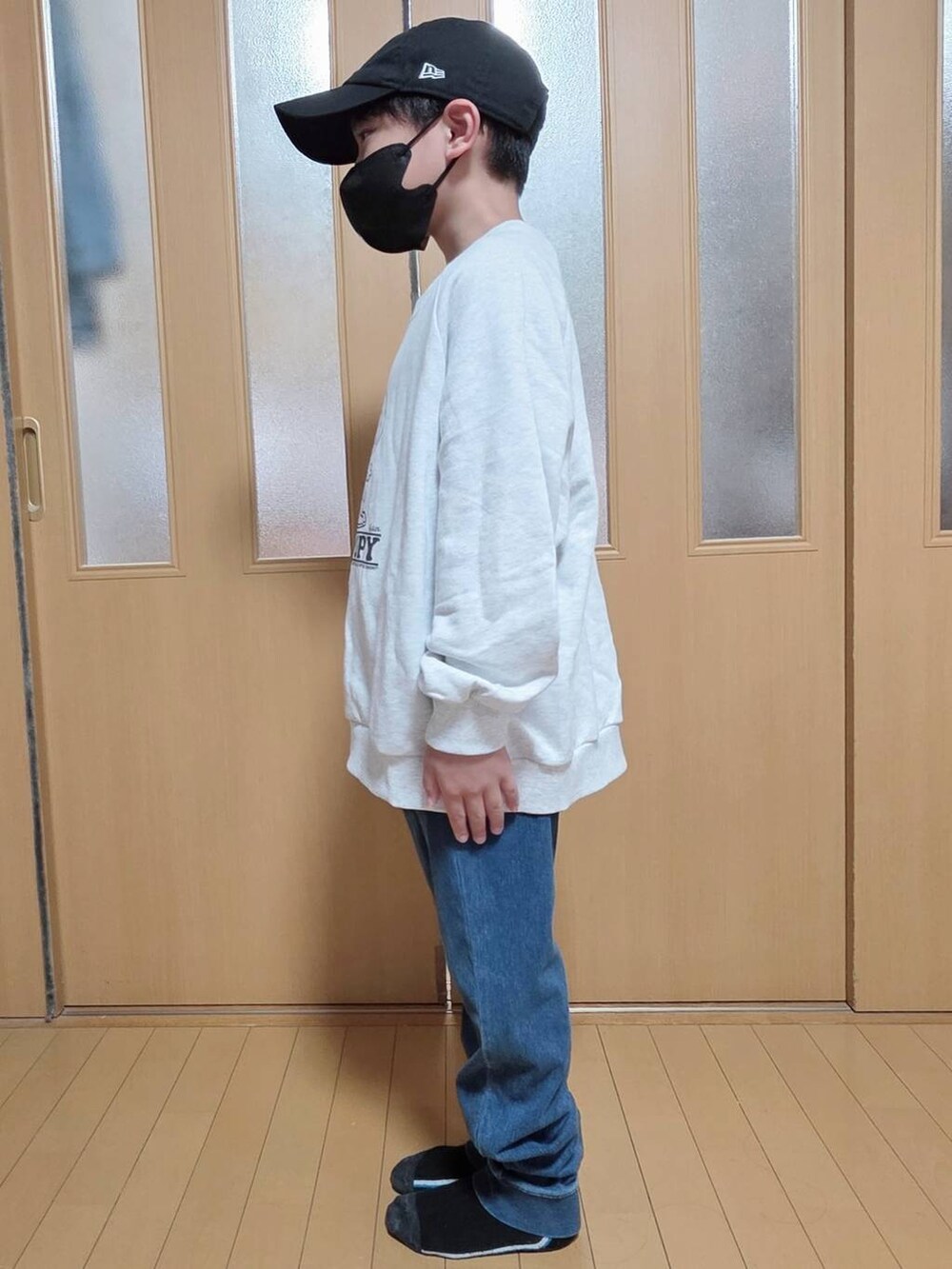 ブルー系のデニムパンツ、グレー系のスウェット、ブラック系のキャップを着用したキッズの秋コーディネートの2枚目の写真