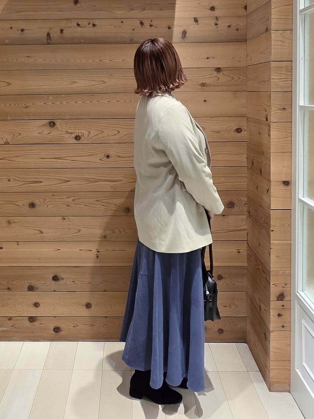 ブラック系のボストンバッグ、ブルー系のスカート、グレー系のニット/セーターを着用したレディースの冬コーディネートの2枚目の写真