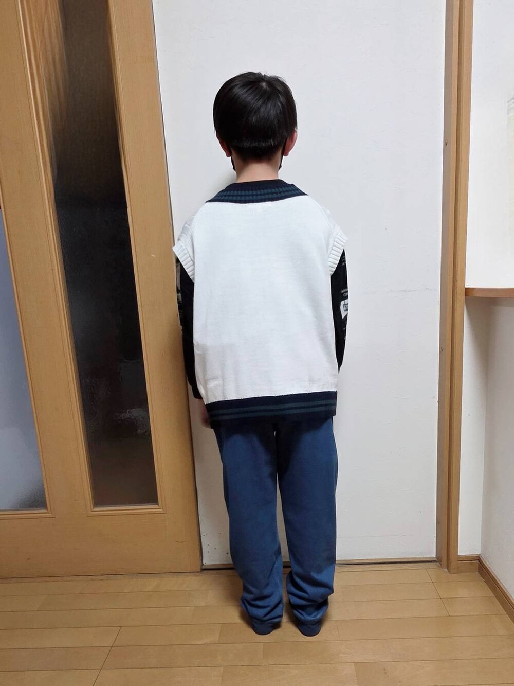 ブルー系のデニムパンツ、ベージュ系のベストを着用したキッズの春コーディネートの3枚目の写真