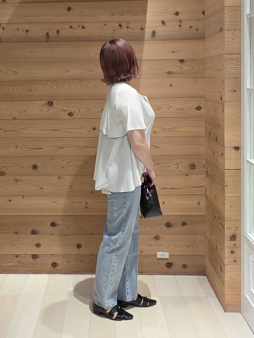 ブラック系のショルダーバッグ、ブルー系のデニムパンツ、ブラック系のタンクトップを着用したレディースの夏コーディネートの2枚目の写真