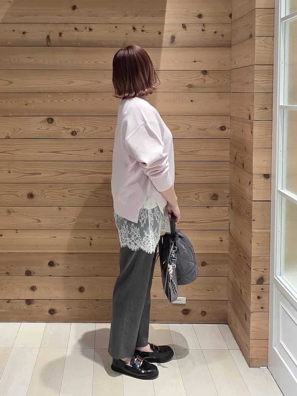 ブラック系のローファー、グレー系のハンドバッグ、グレー系のスラックスを着用したレディースの春コーディネートの2枚目の写真