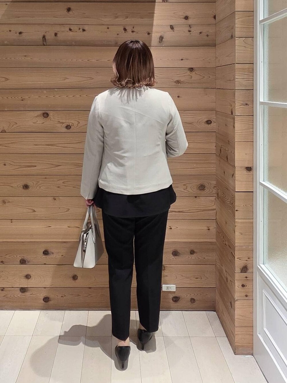 ホワイト系のショルダーバッグ、ブラック系のパンプス、ベージュ系のセットアップを着用したレディースの冬コーディネートの3枚目の写真