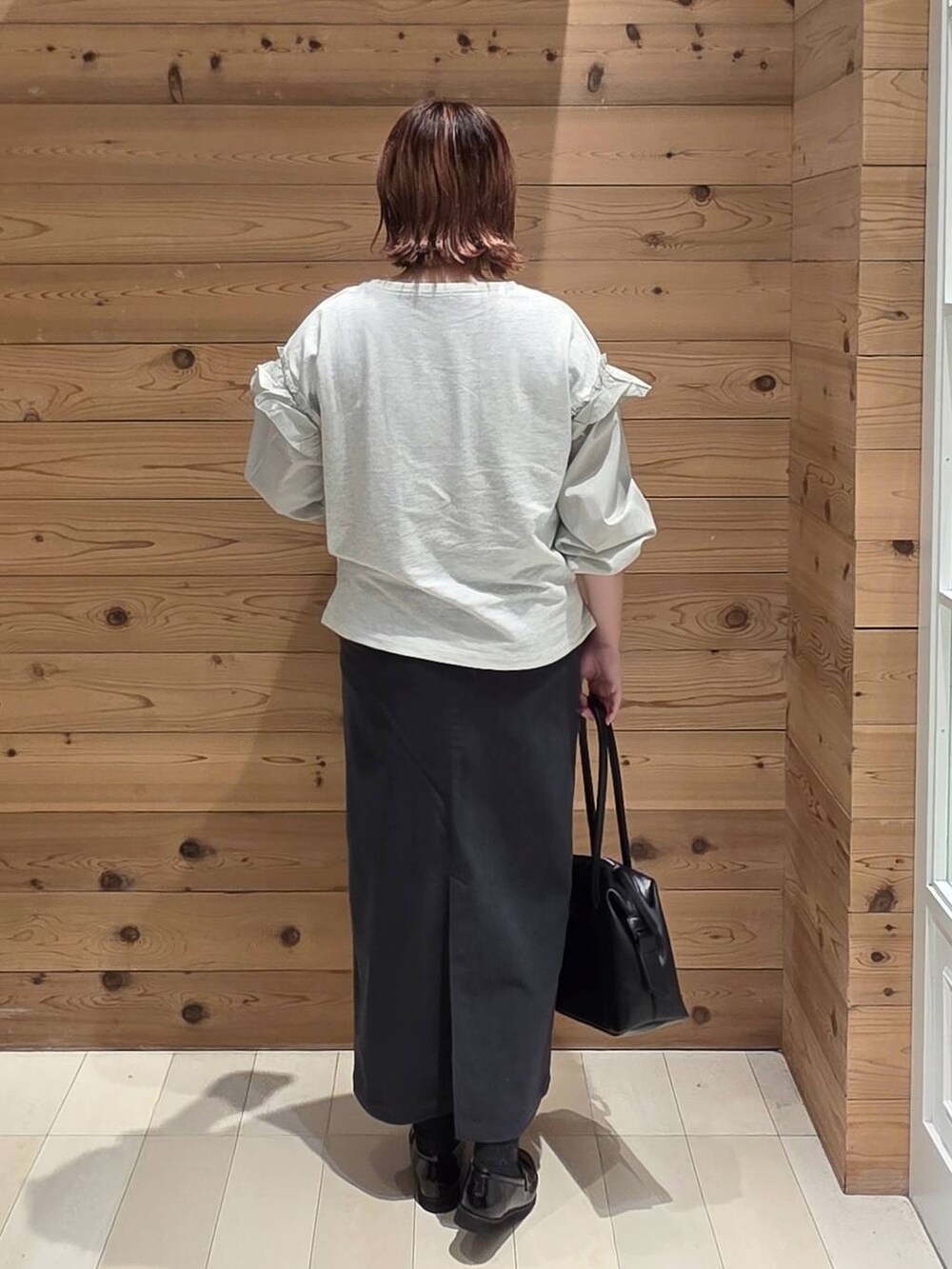 ブラック系のローファー、ブラック系のボストンバッグ、グレー系のスカートを着用したレディースの秋コーディネートの3枚目の写真